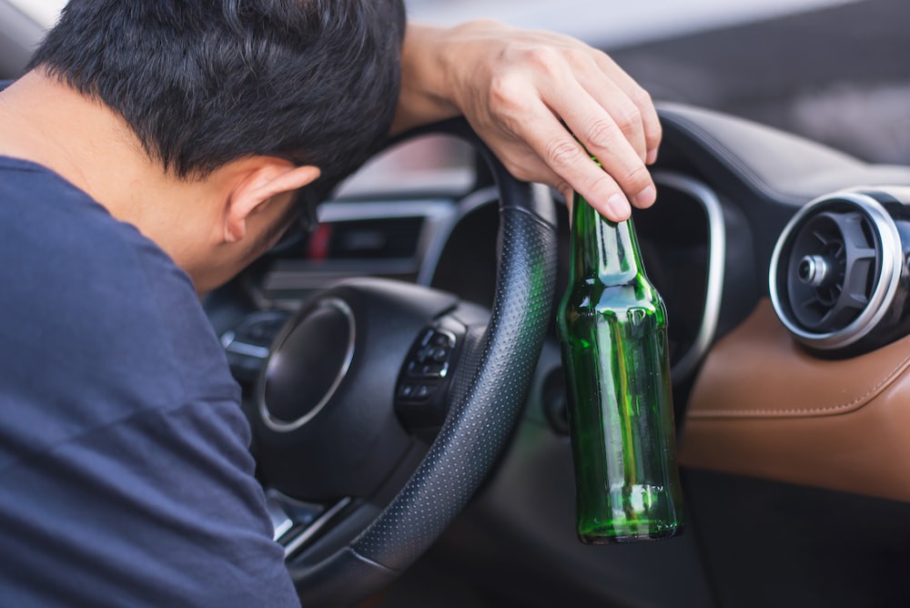 Man behind the wheel with an empty bottle